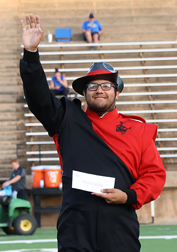 Johnathon Snyder, a junior instrumental music major from Oklahoma City and member of the Ranger Band, waves to the crowd after accepting his $200 tuition prize from the Northwestern Foundation and Alumni.