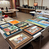 Art entries sitting on tables ready to be processed for the Art Society Art Show.