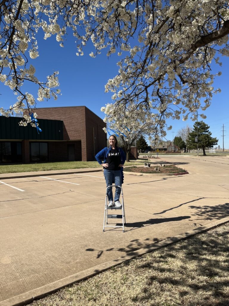 Pictured is Julie Mayer, senior SWAT vice president, with the blue ribbon tree at the Northwestern-Enid campus.
