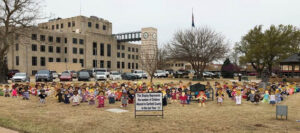 Pictured are (left to right) Levi Sanders, Goltry senior, SWAT president; Annie Moss, Enid senior, SWAT member; and Sierra Miller, Enid senior, SWAT secretary, with the “Wooden Children” at the Garfield County Courthouse.